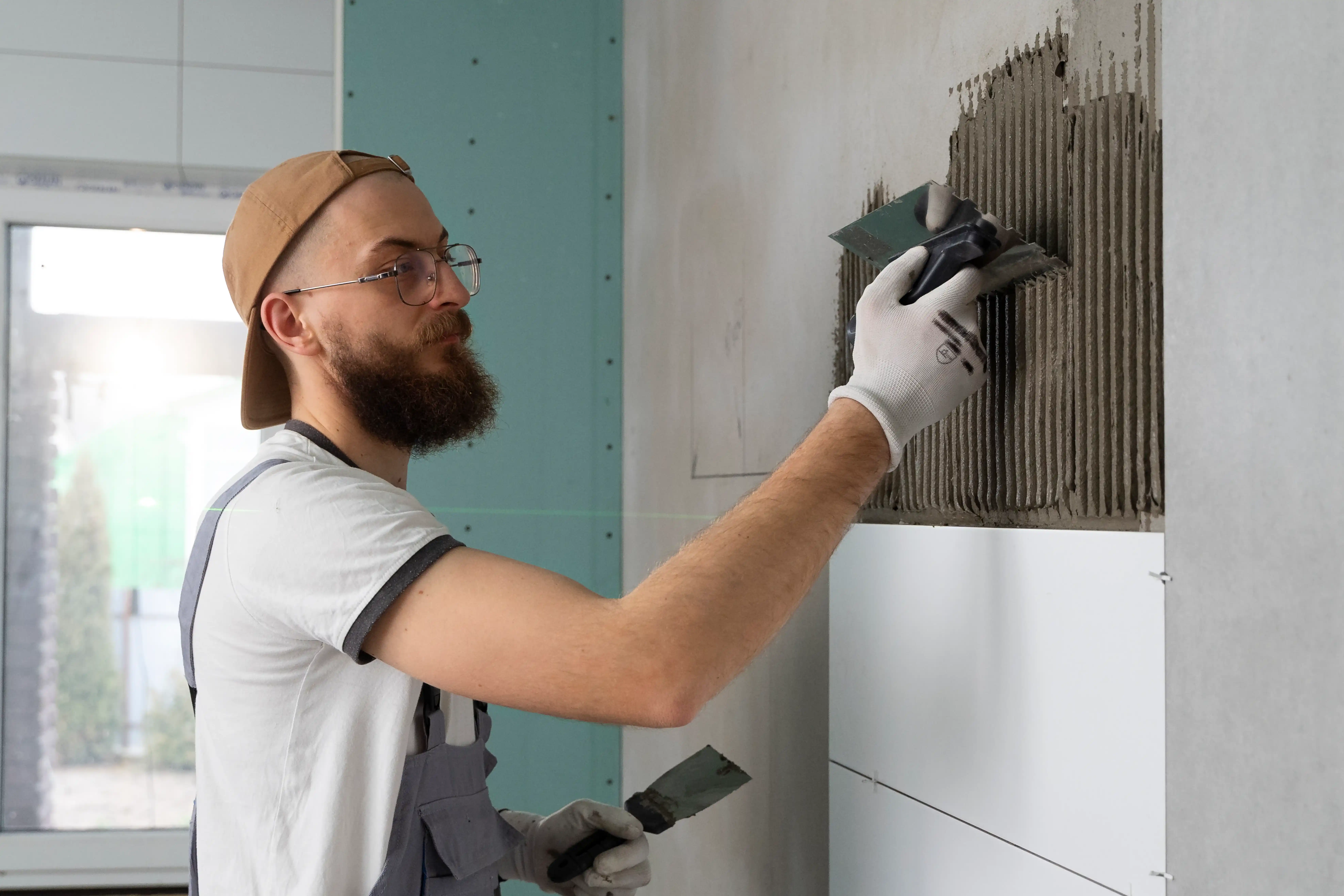 Tiler applying adhesive to a bathroom wall
